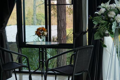 a table and chairs in front of a window with a vase of flowers at Phu Pha View Doi in Samoeng