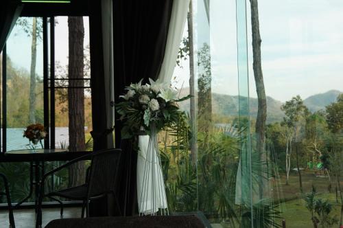 a vase of flowers in a room with a window at Phu Pha View Doi in Samoeng