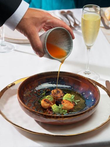 a person is pouring sauce into a bowl of food at The One Palácio da Anunciada in Lisbon
