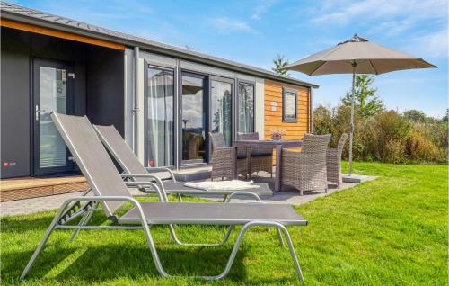 a house with a table and chairs and an umbrella at Chalet 8 Am See in Süsel