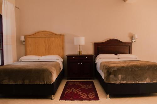 a bedroom with two beds and a table with a lamp at Casa Irene in Teotitlán del Valle