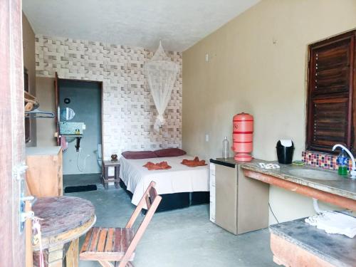 une petite chambre avec un lit et une cuisine dans l'établissement Chalé na Lagoa, à Guriú