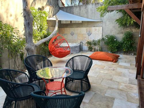 a patio with chairs and a table and a bed at Xainã Pousada de Charme in Cumbuco