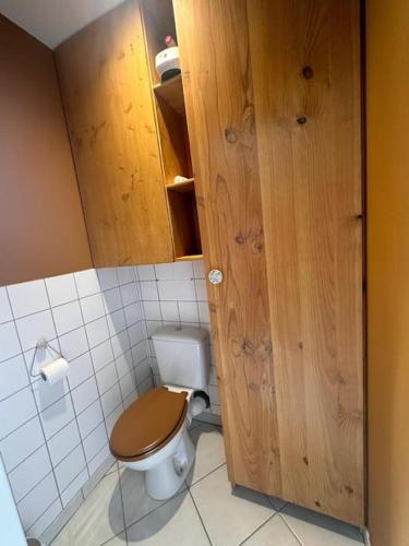 a bathroom with a toilet with a wooden door at Petite maison de village 2 in Saint-Maurice-de-Rémens