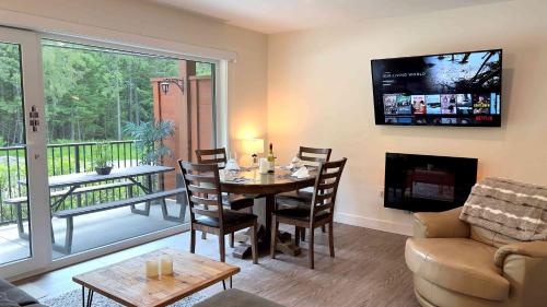 a living room with a dining room table and a balcony at Al's Escape by Revelstoke Vacations in Revelstoke