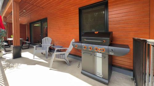 a grill on the side of a house with chairs at Al's Escape by Revelstoke Vacations in Revelstoke