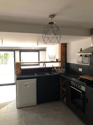 une cuisine avec un évier et une cuisinière four supérieur dans l'établissement Appartement Rez de jardin 1 à 4 pers - 2 chambres, à Collobrières