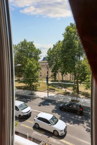 a view from a window of a street with parked cars at Hôtel du Château in Vincennes