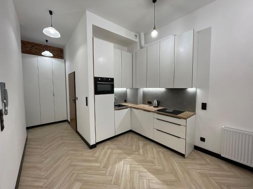 a kitchen with white cabinets and a wooden floor at Pod Błękitnymi Podkowami in Wrocław