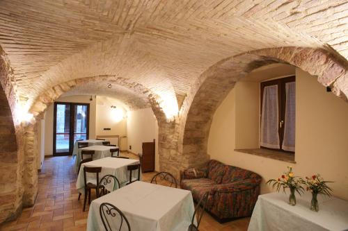 una sala de estar con arcos, mesas y sillas en Albergo La Rocca, en Asís