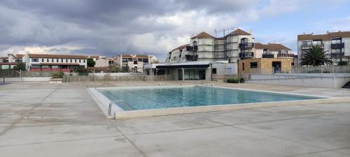 une piscine vide en face de certains bâtiments dans l'établissement Studio avec vue sur l'étang, au Barcarès