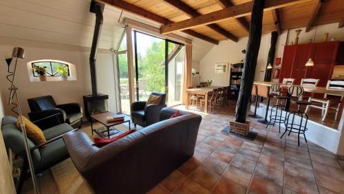 a living room with couches and a table and a kitchen at Sfeervolle groepsaccommodatie met hottub in natuurgebied in Wateren