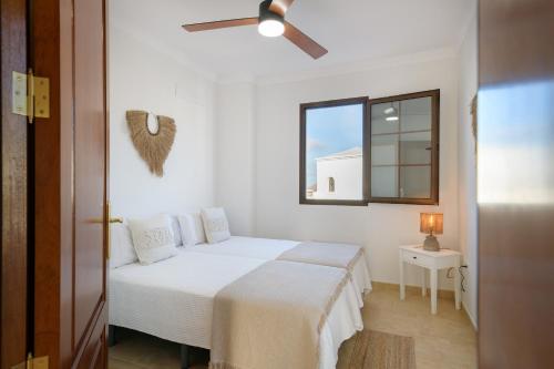 a white bedroom with a bed and a window at Ca Villa Esmeralda, Volcan y Lava in Yaiza