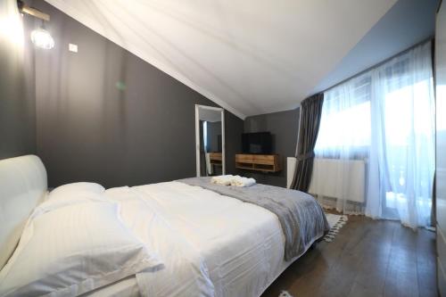 a bedroom with a large bed and a large window at Pensiunea La Ancuța-n Bucovina in Voronet