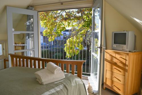 a bedroom with a bed and a tv and a balcony at Pear Tree Cottage in Shaldon