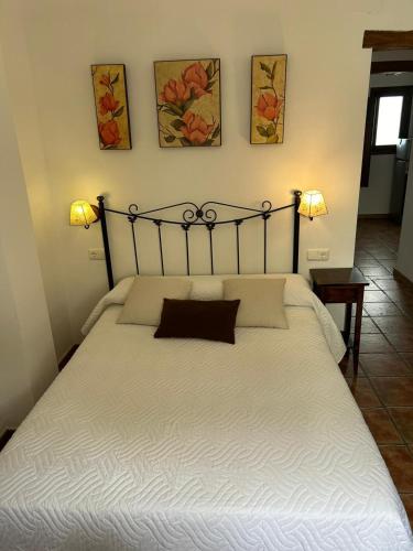 a bed in a bedroom with two lamps on the wall at Muley Hacén in Capileira