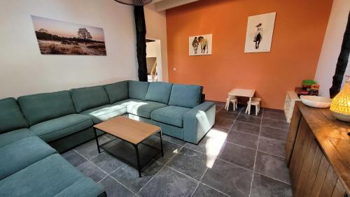 a living room with a blue couch and a table at Sfeervolle groepsaccommodatie met hottub in natuurgebied in Wateren