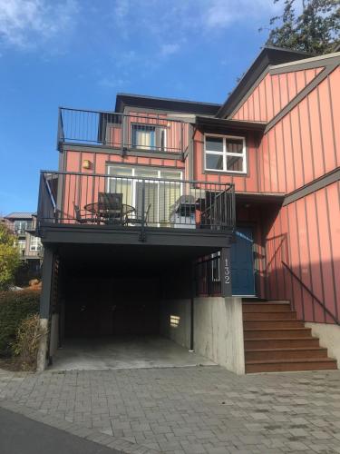 a large red house with a balcony on top of it at Sooke Harbour Townhouse in Sooke