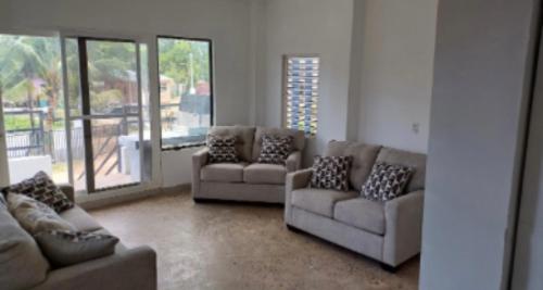 a living room with couches and a large window at Dove Escapes- 2 bdrm appt in village of Placencia in Placencia Village