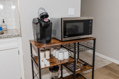 a microwave oven sitting on a shelf with mugs at Midcentury Modern 2br Comfort Near The Greene! in Kettering