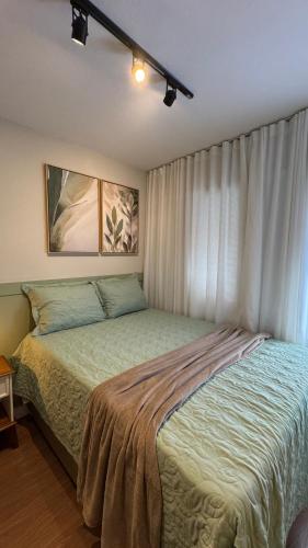a bedroom with a bed and a window with curtains at Apê Coloridinho - Centro in Serra Negra
