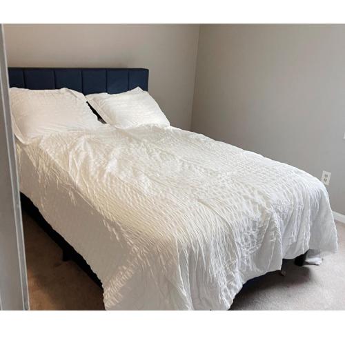 a bed with white sheets and a blue headboard at Comfortable Tuscaloosa Retreat in Tuscaloosa