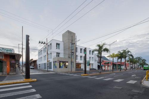 an empty city street with a white building and palm trees at Lusitania Suites in Orizaba