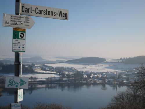 a street sign with a view of a lake at Ferienwohnungen Haus Hinneres in Schalkenmehren