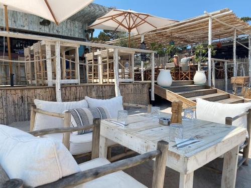 - une table en bois avec des chaises et un parasol sur la terrasse dans l'établissement Rez-de-jardin 6 - Accès direct à la plage, à Calvi