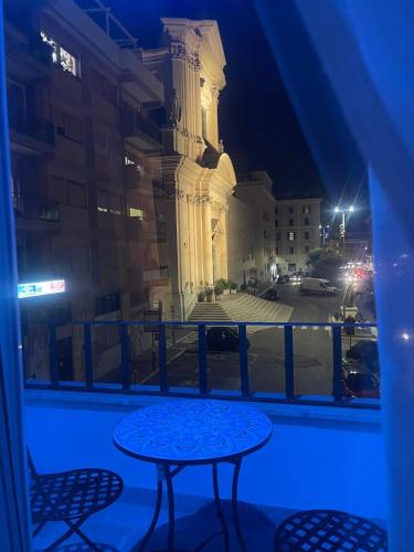 a balcony with a table and a clock tower at night at La Dolce Vita Civitavecchia in Civitavecchia