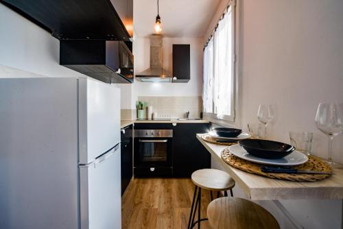 - une cuisine avec des armoires noires et un réfrigérateur blanc dans l'établissement Le Mirage Des Sables - Parking - Netflix, à Tours