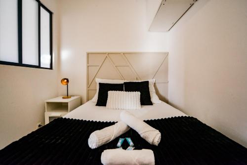 - une chambre dotée d'un lit avec des draps noirs et blancs dans l'établissement Le Mirage Des Sables - Parking - Netflix, à Tours