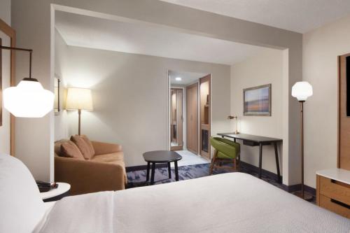 a hotel room with a bed and a couch and a desk at Fairfield Inn & Suites by Marriott Charleston in Charleston