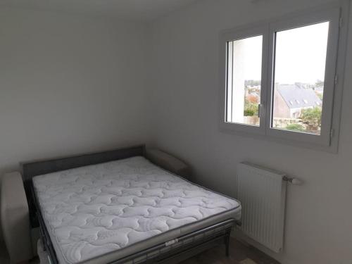 a bed sitting in a room with a window at Gîte à 400m de la mer in Ploudalmézeau