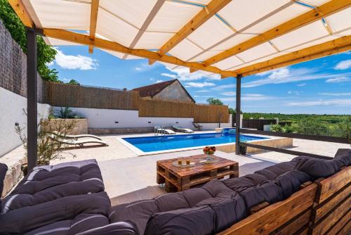 a patio with a couch and a table and a pool at MY DALMATIA - Holiday home Agro Casa with private heated pool in Skradin