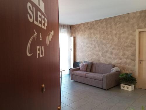 una sala de estar con sofá y un cartel que dice que dormir es un intento en Sleep & Fly BGY Airport-Station-Center, en Bérgamo