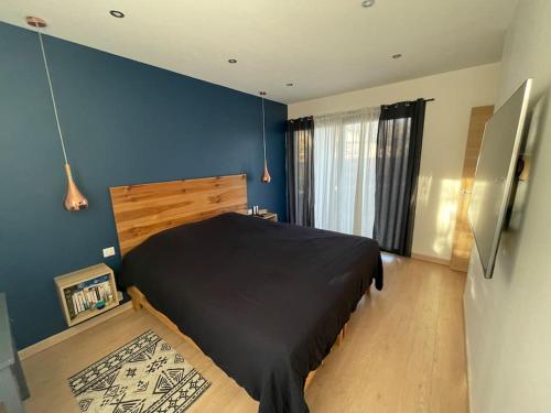 - une chambre avec un lit noir et un mur bleu dans l'établissement Maison d'Architecte - 15 min Toulouse - Piscine, à Belberaud