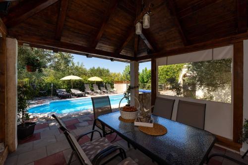 un patio con tavolo e sedie e una piscina di MY DALMATIA - Holiday home Olive Garden with private swimming pool a Lađevci