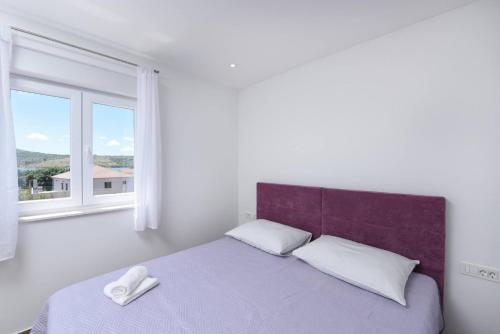 a bedroom with a bed with a purple headboard and a window at MY DALMATIA - Sea view villa Possedaria with amazing roof terrace in Posedarje