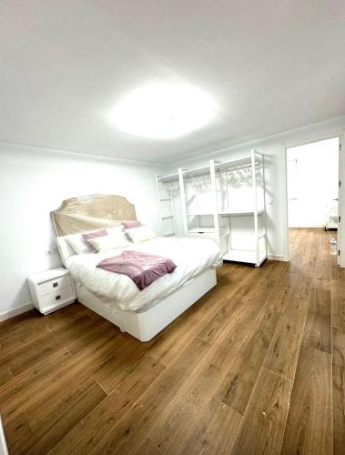 a bedroom with a white bed and a wooden floor at Casa rural in Cabra