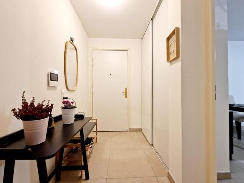 un couloir doté d'une table avec deux plantes en pot dans l'établissement Appartement aux portes de Paris, à Aubervilliers