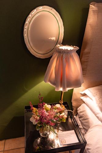a table with a lamp and a mirror and flowers at Sionsberg Farmstay in Riversdale