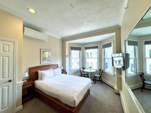 a bedroom with a bed and a table and windows at Copley House in Boston
