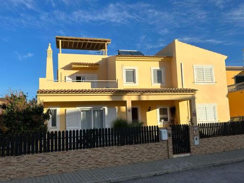 a yellow house with a fence and a lighthouse at vila pinheiro in Bias do Norte