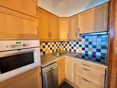 une cuisine avec des armoires en bois et un évier dans l'établissement Résidence Lac Du Lou - Appartement 4 pers exposé Sud au coeur des Menuires MAE-5584, aux Menuires