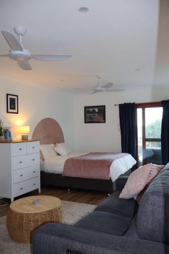 a living room with a bed and a couch and a bed and a room with at Bluebell Cottage in Beechmont