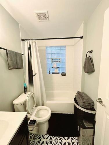 a bathroom with a toilet and a bath tub with a window at Cozy & Near Downtown & Hyde Park in Chicago