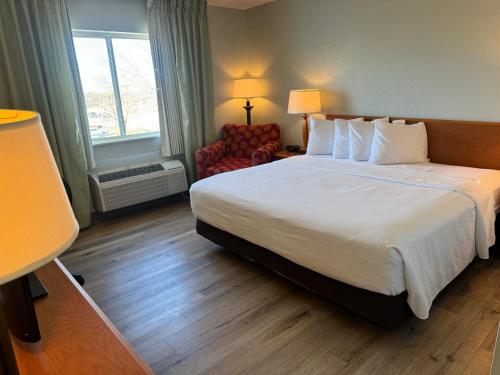 a hotel room with a large bed and a chair at Wingate by Wyndham Sioux City in Sioux City