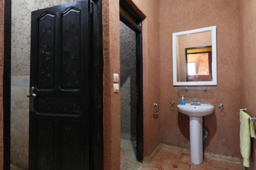 baño con puerta negra y lavamanos en Gite Ogog Tacheddirt, en Tacheddirt