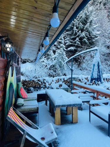 a snow covered porch with a picnic table and benches at Wooden Huts In Mestia in Mestia